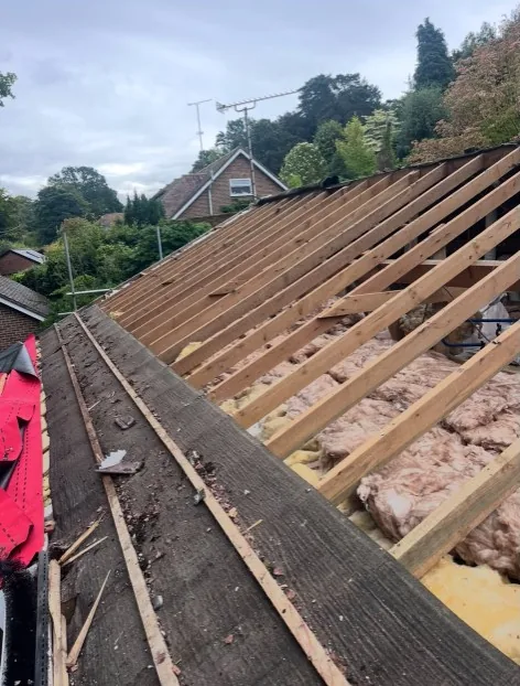 completed hip roof with reddish-brown tiles under a clear blue sky in Farnborough — Mitchell's Roofing
