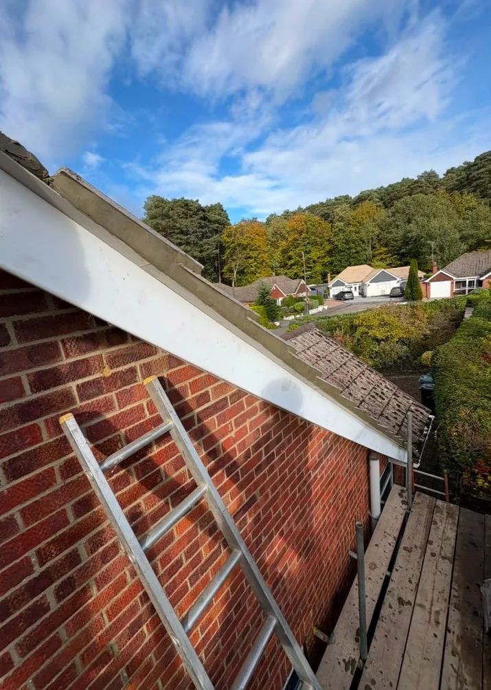 new white fascia and roof verge work on a brick house with scaffolding in Odiham — Mitchell's Roofing