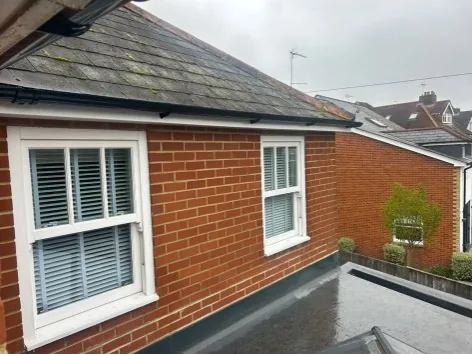 flat roof adjoining a pitched tiled roof on a brick residential property in Frimley — Mitchell's Roofing
