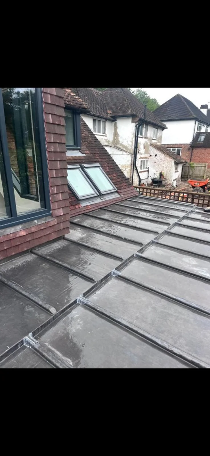 new grey metal flat roof with raised seams adjoining a clay tiled roof and skylights in Bentley — Mitchell's Roofing