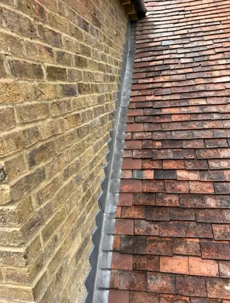stepped lead flashing at a tiled roof and brick wall abutment in Hook — Mitchell's Roofing