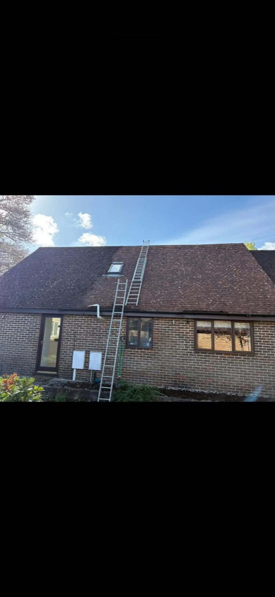 before and after moss removal on a tiled roof showing cleaned terracotta tiles in Godalming — Mitchell's Roofing
