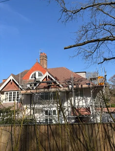 tile repair at the roof verge with battens exposed and scaffolding below in Sandhurst — Mitchell's Roofing